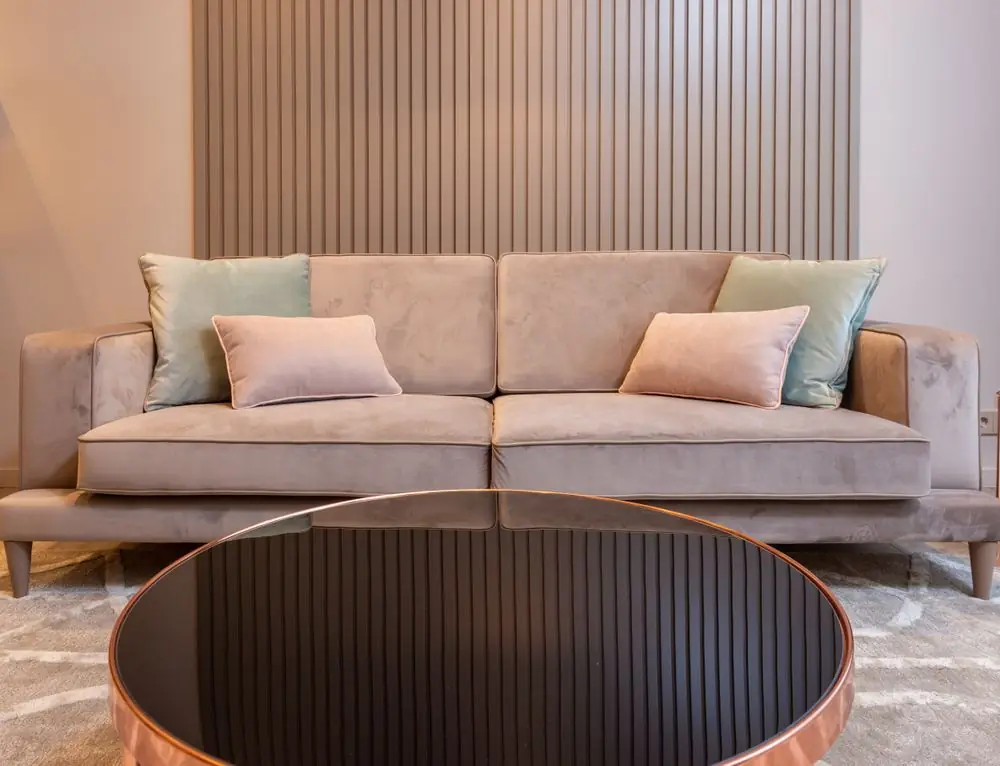 Slatted wood wall behind a beige sofa and low table