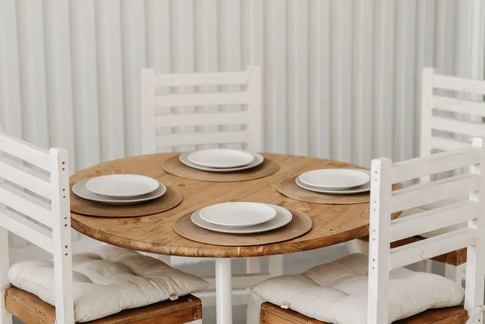 Round wooden dining table with four white chairs